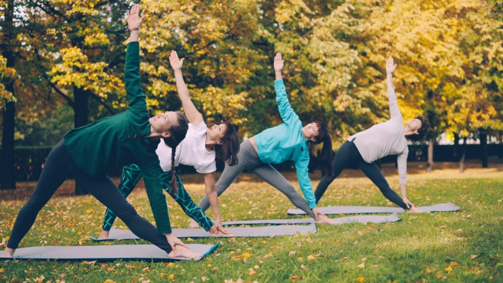 A group of adults practicing yoga outdoors on a sunny autumn day.